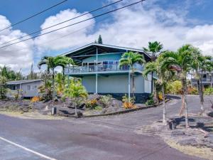 a blue house with palm trees in front of it at Hawaiian Paradise in Keaau
