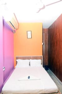 Bett in einem Zimmer mit orangefarbener Wand in der Unterkunft Tusthi Banquets in Kalkutta