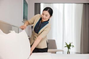 南京南京金融城辉盛名致公寓酒店的一位女士站在房间的床边