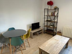 - un salon avec une table, des chaises et une télévision dans l'établissement Apartamentos Garnacha 1 totalmente reformado, à Saragosse