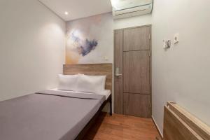 Habitación pequeña con cama y puerta en Livinn Juanda Airport Surabaya en Sidoarjo