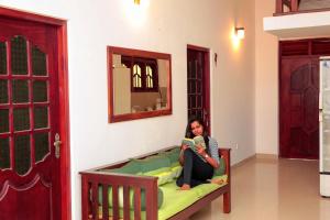 a woman sitting on a couch reading a book at Pearl Mirissa in Mirissa