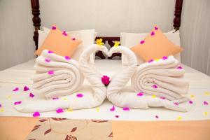 two towels shaped like swans sitting on a bed at Pearl Mirissa in Mirissa