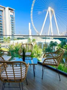 a balcony with chairs and a ferris wheel in the background at Nasma Luxury Stays - Blue Waters Island in Dubai