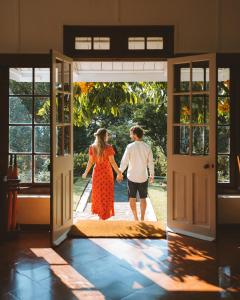 a man and woman walking through an open door at Mountbatten Bungalow- Thema Collection in Kandy