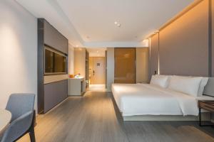 a bedroom with a large white bed and a table at Atour Hotel Nanjing Olympics Sports Center CBD in Nanjing