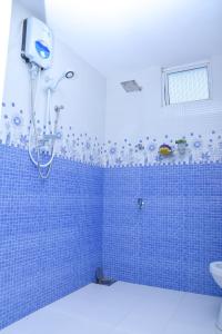 a blue tiled bathroom with a shower and a sink at Rashmi HomeStay in Balapitiya