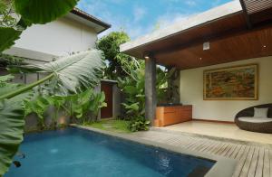 a villa with a swimming pool and a house at JAPA Suites & Villas in Ubud