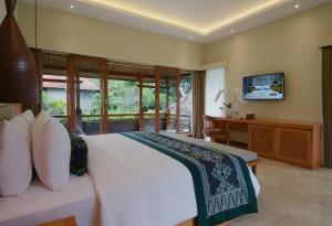 a bedroom with a bed and a desk and a television at JAPA Suites & Villas in Ubud