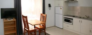 a small kitchen with a table and a refrigerator at Footscray Motor Inn and Serviced Apartments in Melbourne