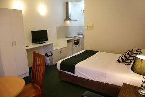 1 dormitorio con 1 cama y escritorio con TV en Footscray Motor Inn and Serviced Apartments, en Melbourne