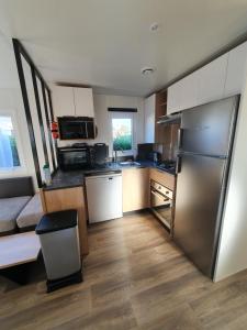 una pequeña cocina con nevera de acero inoxidable en Mobil Home 2022 les charmettes 3 Chambres 40m2, en Les Mathes