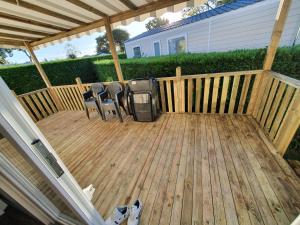 a wooden deck with two chairs and a television on it at Mobil Home 2022 les charmettes 3 Chambres 40m2 in Les Mathes