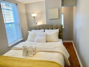 1 dormitorio con 1 cama blanca grande y ventana en Upscale 2BD/1.5BA townhome mins to JHH & downtown en Baltimore