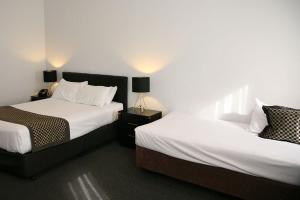 two beds in a hotel room with two lamps at Footscray Motor Inn and Serviced Apartments in Melbourne