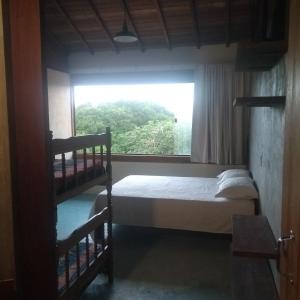 a bedroom with two bunk beds and a window at Pousada Recanto Devas in Cabo Frio