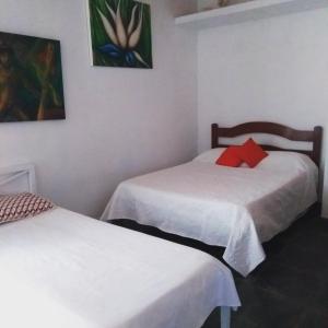 a room with two beds and a painting on the wall at Pousada Recanto Devas in Cabo Frio