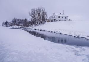 Myvo The House Geiteyjarströnd 4 في Geiteyjarstrond: منزل على تل مغطى بالثلج بجوار نهر