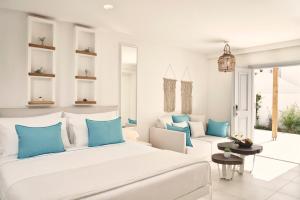 1 dormitorio con 1 cama blanca grande y almohadas azules en Nikki Beach Resort & Spa Santorini en Kamari