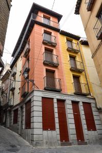 a building with red doors and balconies on a street at Apartamentos Turísticos Toledo in Toledo