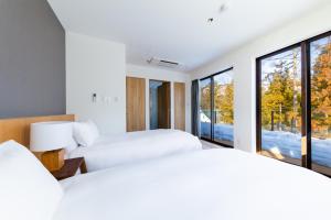 two beds in a room with large windows at ROKA by HHG in Hakuba