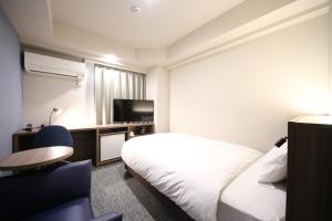 una camera d'albergo con letto e TV di Hotel Kajigaya Plaza a Kawasaki