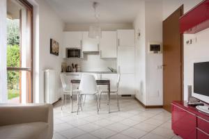 uma cozinha com armários brancos e uma mesa e cadeiras em Casa Cariza-Appartamento con piscina em Colà di Lazise