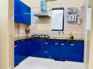 a blue kitchen with a stove and blue cabinets at Olive Service Apartments - Artemis in Gurgaon