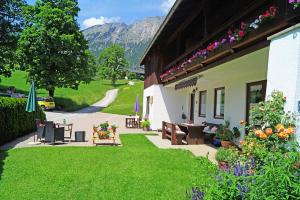 uma casa com um quintal com bancos e flores em Ferienwohnungen Haus Sonnseitn em Berchtesgaden