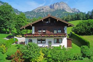 uma casa numa colina com uma montanha ao fundo em Ferienwohnungen Haus Sonnseitn em Berchtesgaden