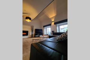 ein Wohnzimmer mit einem schwarzen Sofa und einem Kamin in der Unterkunft Phils Cottages - Gîte - Vakantiewoning Philled With Love in Érezée
