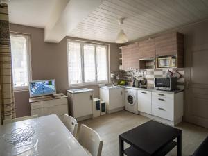 a kitchen with white cabinets and a table and a dining room at Appartement Mont Dore face aux Thermes - Centre in Le Mont-Dore +2 photos