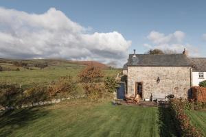 una casa de piedra en un campo con un patio en Widecombe Cottage, en Widecombe in the Moor