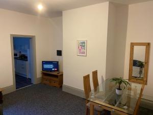 ein Wohnzimmer mit einem Glastisch und einem TV in der Unterkunft Newcastle Apartment 3 - Free Parking in Old Walker