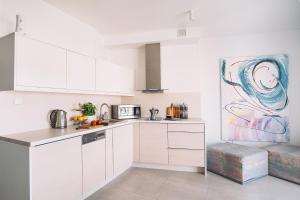 a kitchen with white cabinets and a painting on the wall at Apartament Blue Sky in Hel +16 photos