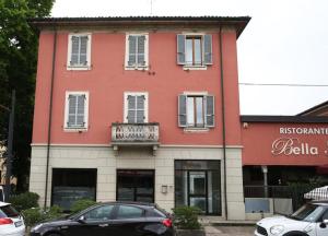 a red building with a balcony and cars parked in front at La Francigena - Trebbia House in Piacenza