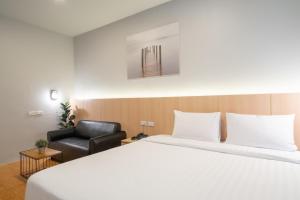 Habitación de hotel con cama y silla en The Arbern Hotel x Bistro - SHA Extra Plus, en Phuket
