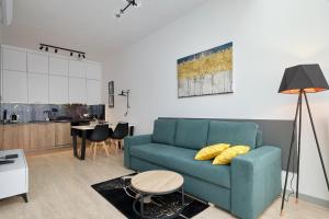 a living room with a blue couch and a kitchen at Green Ande in Wrocław