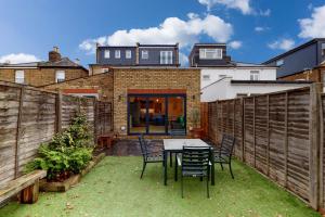 un patio con mesa y sillas en un patio trasero en Beautiful 3 bed house 30 mins from Central London en Kingston upon Thames