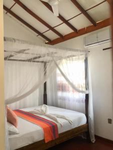 ウェリガマにあるThe Sea View Villa Surf Schoolのベッドルーム1室(天蓋付きベッド1台、窓付)