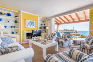 un salon avec des chaises, une table et une télévision dans l'établissement Villa Front a Far, à Portocolom