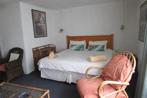 a bedroom with a large bed and a chair at Absolute Leisure Cottages in Machadodorp