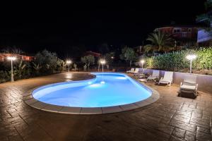 a swimming pool at night with chairs and lights at Residenza Borgo Italico in Santa Domenica