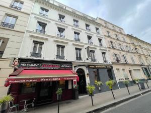 un gran edificio blanco en una calle con una tienda en Hotel de Paris Montmartre, en París