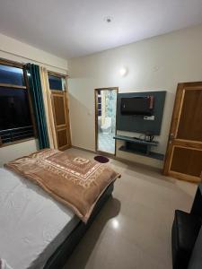 een slaapkamer met een bed en een flatscreen-tv bij Ranas B&B in Shimla