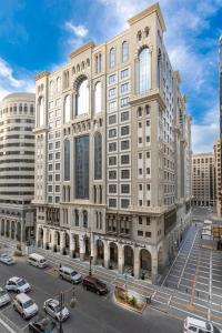 ein großes Gebäude mit davor geparkt in der Unterkunft Al Aqeeq Madinah Hotel in Medina