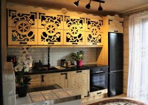 a kitchen with wooden cabinets and a black refrigerator at Domek Góralski Piwowarówka in Piwniczna-Zdrój
