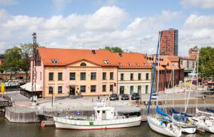 eine Gruppe von Booten, die in einem Yachthafen mit einem Gebäude angedockt sind in der Unterkunft Old Mill Comfort in Klaipėda