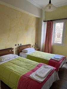 a hotel room with two beds and a window at Hotel Koutriaris in Distomo