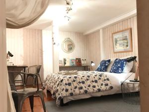 a bedroom with a bed with blue and white sheets and a table at Villa Toscane - Atelier d'Artistes et B&B à 20 mn de Toulouse in Azas